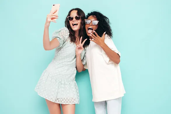two girls in light clothing posing for a selfie