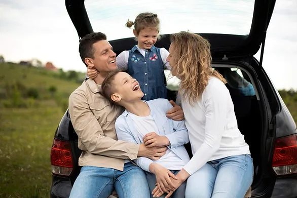 family of four sitting on trunk of car