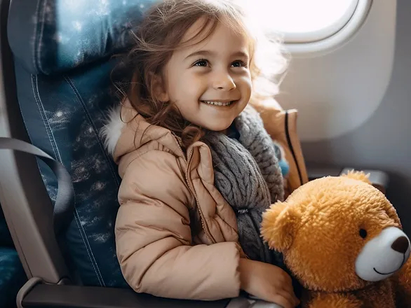 a heartwarming image of a happy child sitting in a plane seat, looking out the window with wide-eyed wonder and a joyful smile. The child is comfortably dressed for travel and is surrounded by a few travel essentials like a small backpack, a stuffed animal, and a colorful book. The atmosphere in the plane is cozy and welcoming, with soft cabin lighting that adds to the child's excitement and happiness about the journey ahead.