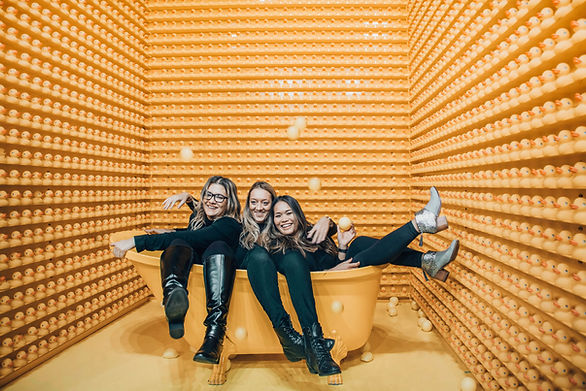 three girls in a bathtub with room of rubber ducks