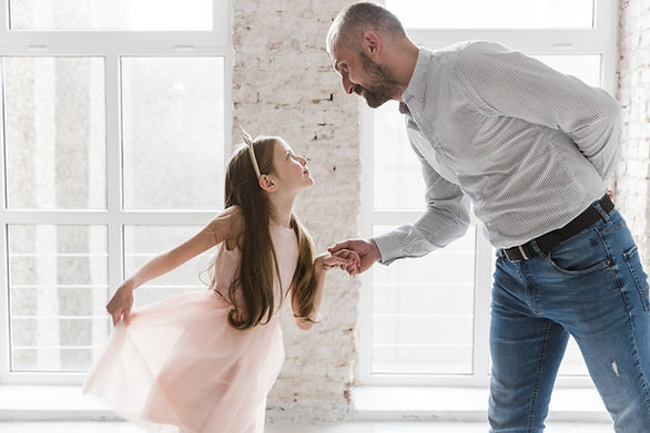 young girl in a pink dress holding dads hand about to dance