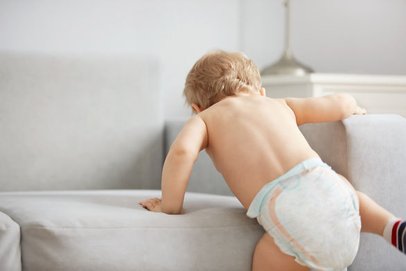 baby boy in diaper climbing on couch