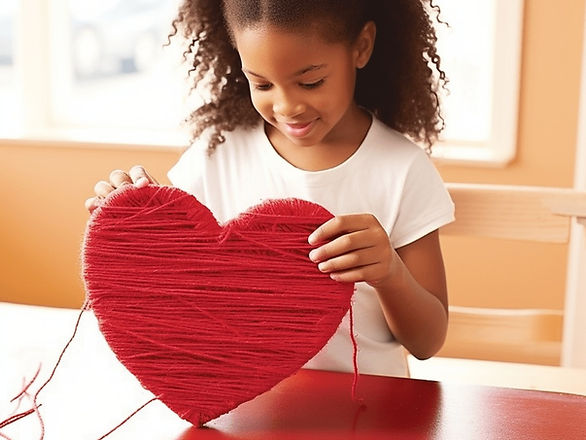 valentine crafts for kids girl wrapping red yarn around a cardboard heart 