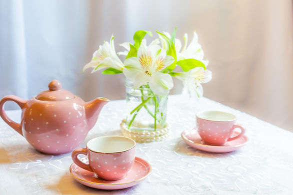 two tea cups, a kettle and flowers in a vase - kids tea party ideas