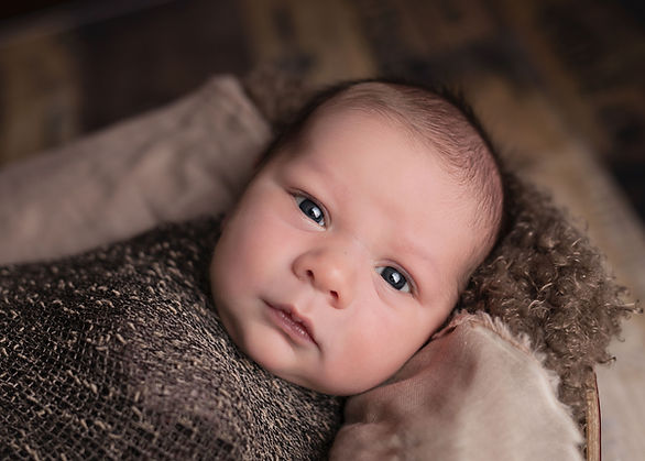 infant staring wrapped in brown cloth