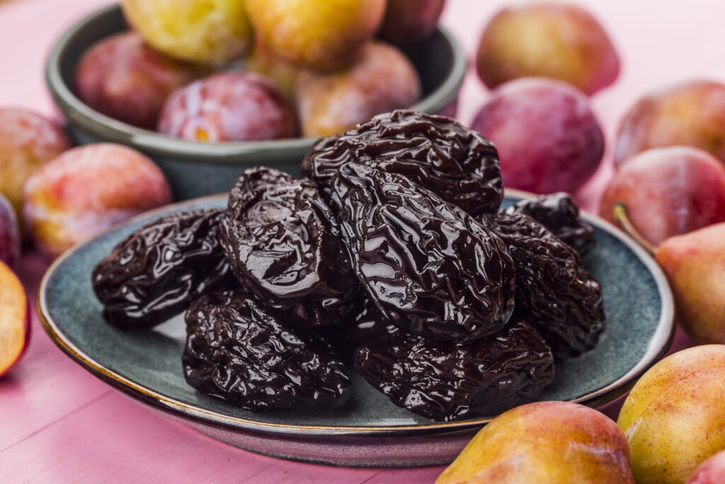 home remedies for constipation - plate of prunes surrounded by whole fruits 