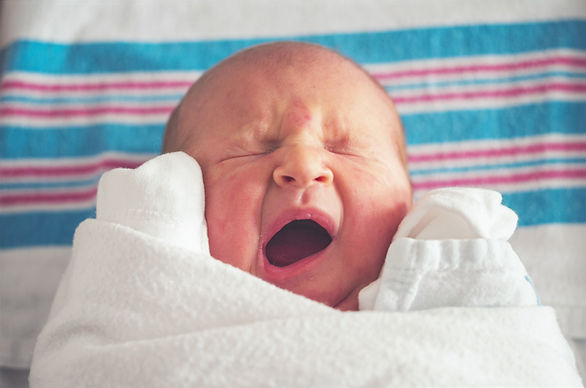 baby swaddled and yawning