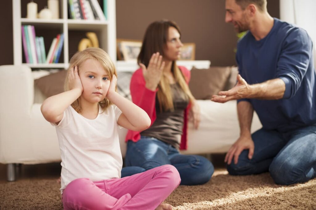 little girl holding ears while parents are fighting: parenting class for divorce