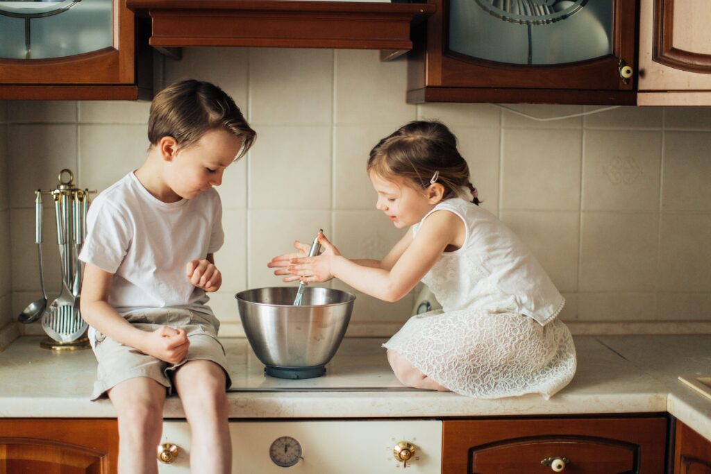boy and girl sitting on counter with a mixing bowl