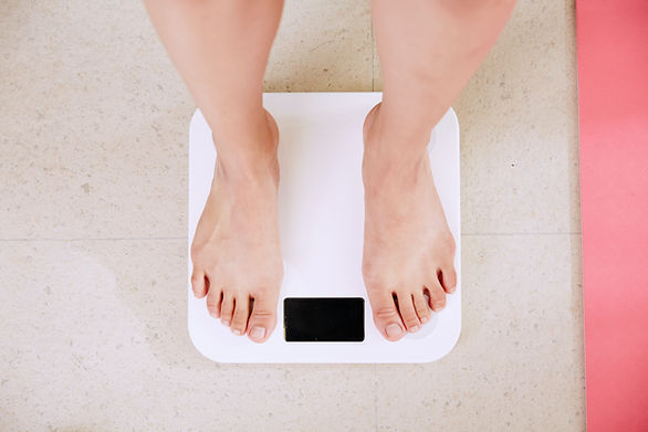 diet of 1200 calories - woman standing on scale, only bottom of legs and feet showing