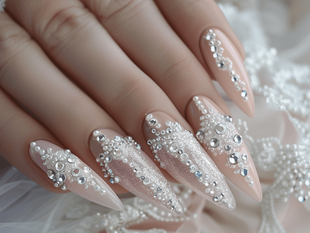 Luxurious almond-shaped mob wife nails in a soft blush pink, adorned with white lace details and small, shimmering diamond-like stones.