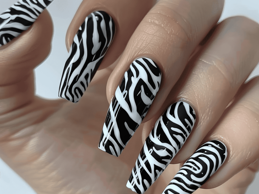 Long coffin-shaped nails with a bold black and white zebra print design for a classic mob wife look.