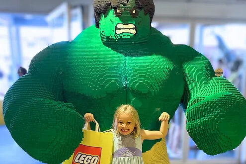 shopping in Disney Springs - small blonde girl holding a Lego bag with a large Lego Hulk figure behind her