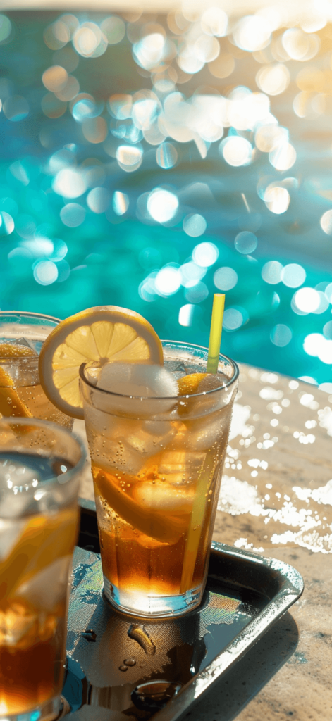 A close-up of a tray with refreshing summer drinks--iced tea, lemonade, and cocktails--next to a shimmering pool under the bright sun. It’s ideal for evoking the relaxing vibe of summer lounging. 