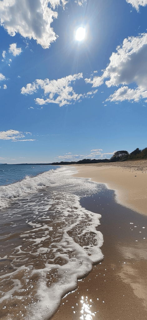 A serene beach with gentle waves lapping at the shore, under a bright sunny sky. 