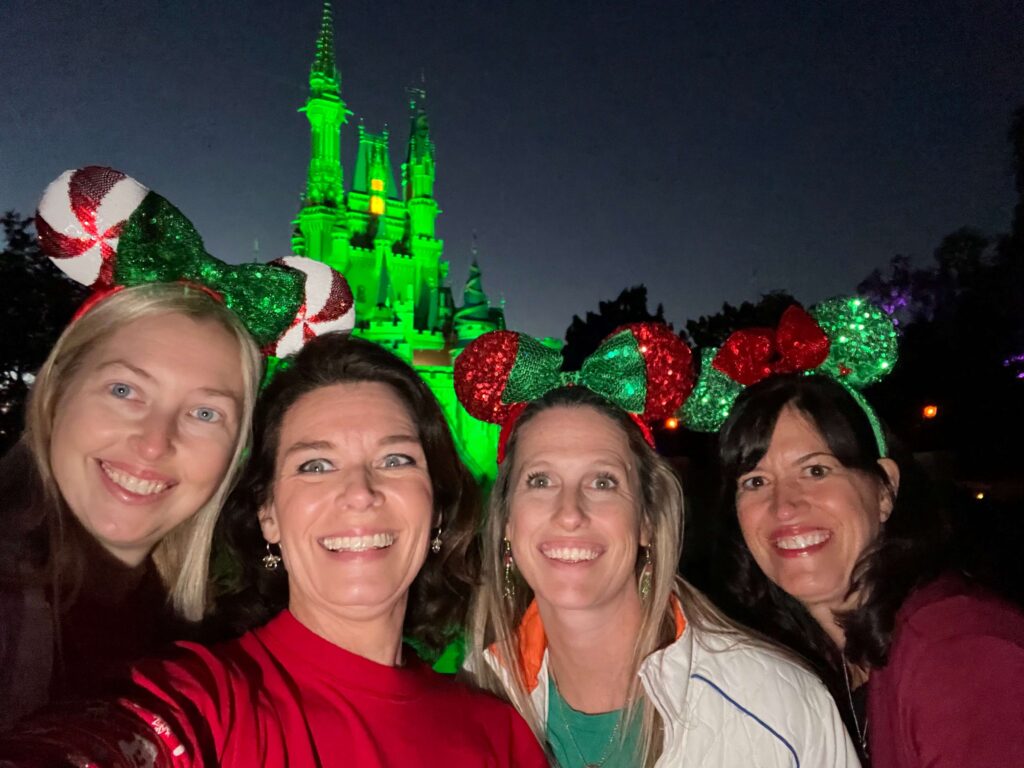 4 women in front of the Disney castle, three wearing Mickey ears