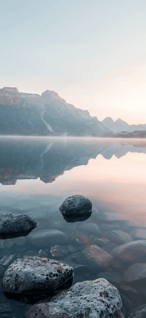 Calm lake at dawn with mist rising from the water and mountains in the distance. iphone wallpaper summer