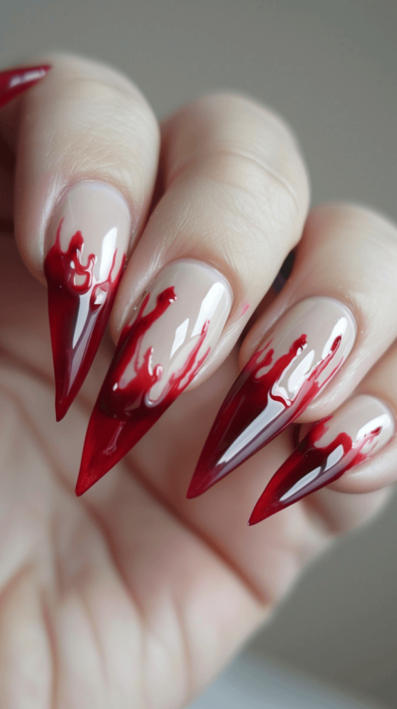 Nails with a beige or pale pink base and red polish creating a dripping blood effect at the tips. The drips vary in length and thickness for a dramatic look.