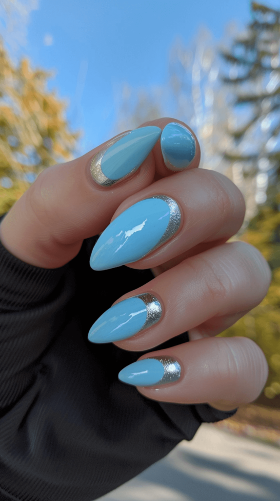 A manicured hand with light blue nails with silver tips representing Cinderella.