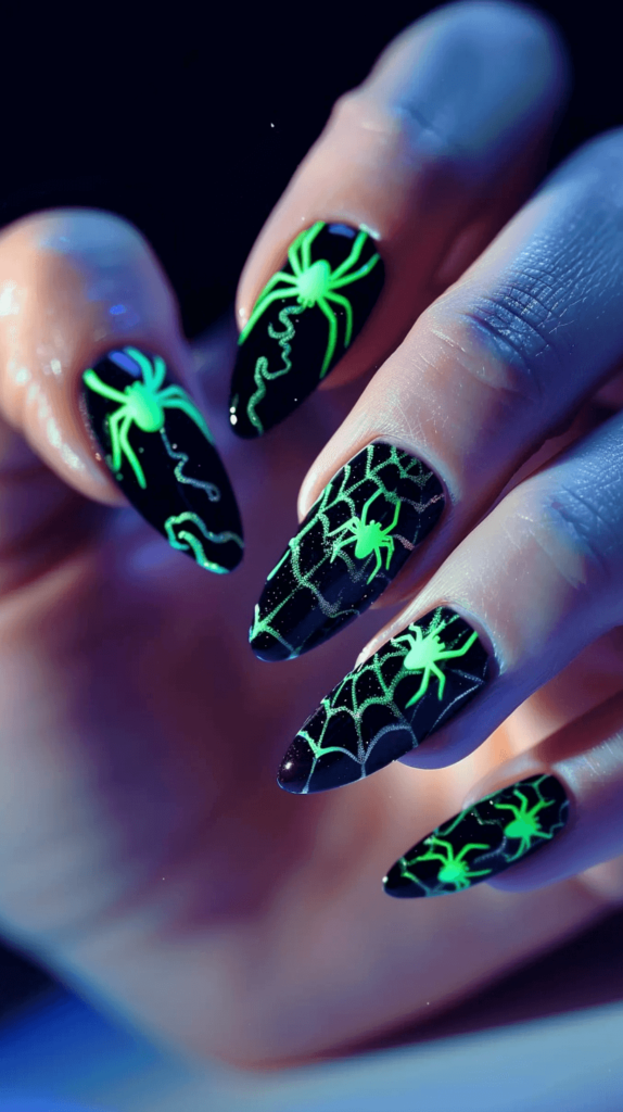 Nails with a glow-in-the-dark polish base. Some nails feature simple designs like stars or ghosts, while others have more intricate patterns. The glow effect is visible in a dark setting.