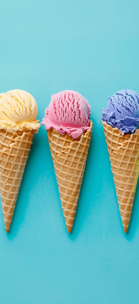 Brightly colored ice cream cones in a row against a light blue backdrop.
