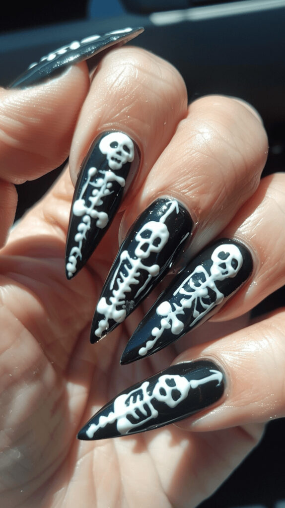 Black nails with white skeleton bone designs. Some nails feature full skeletons, while others have just bones or skulls for a spooky effect. 