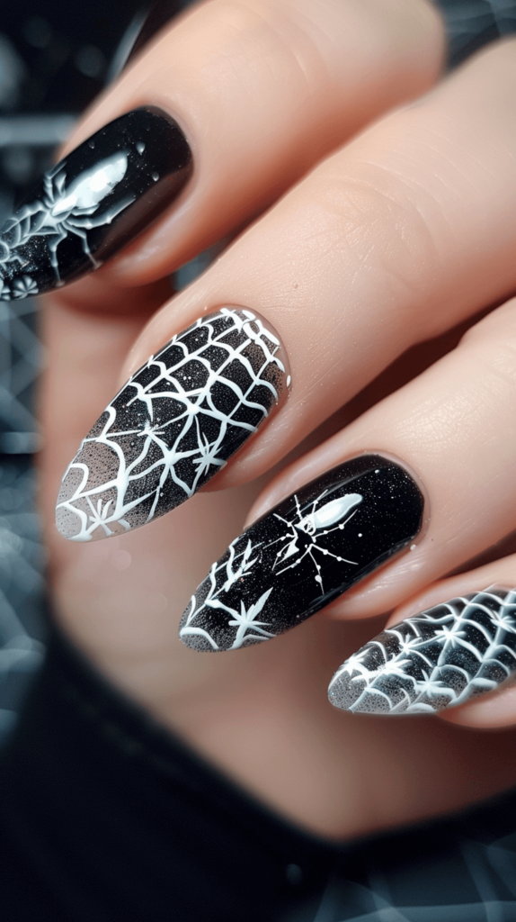 Close-up of nails with a black base and intricate white spider web designs on each nail. One nail features a tiny black spider hanging from the web.