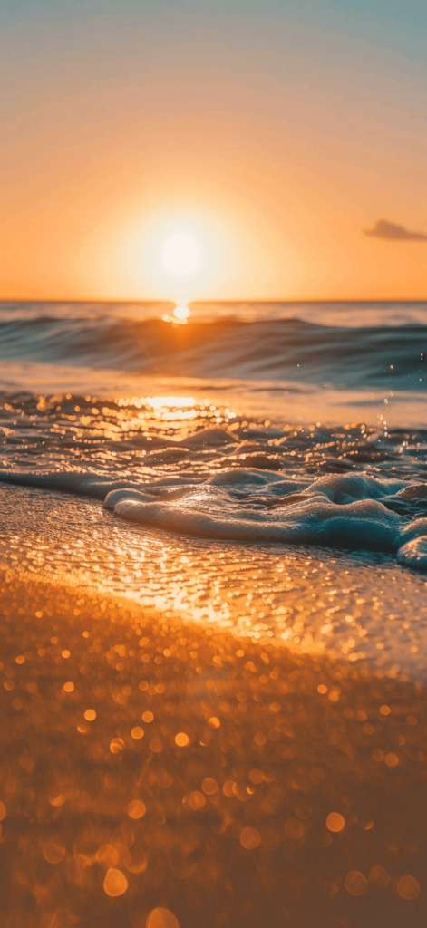 A sandy beach at golden hour, as the sun sets over the horizon.

