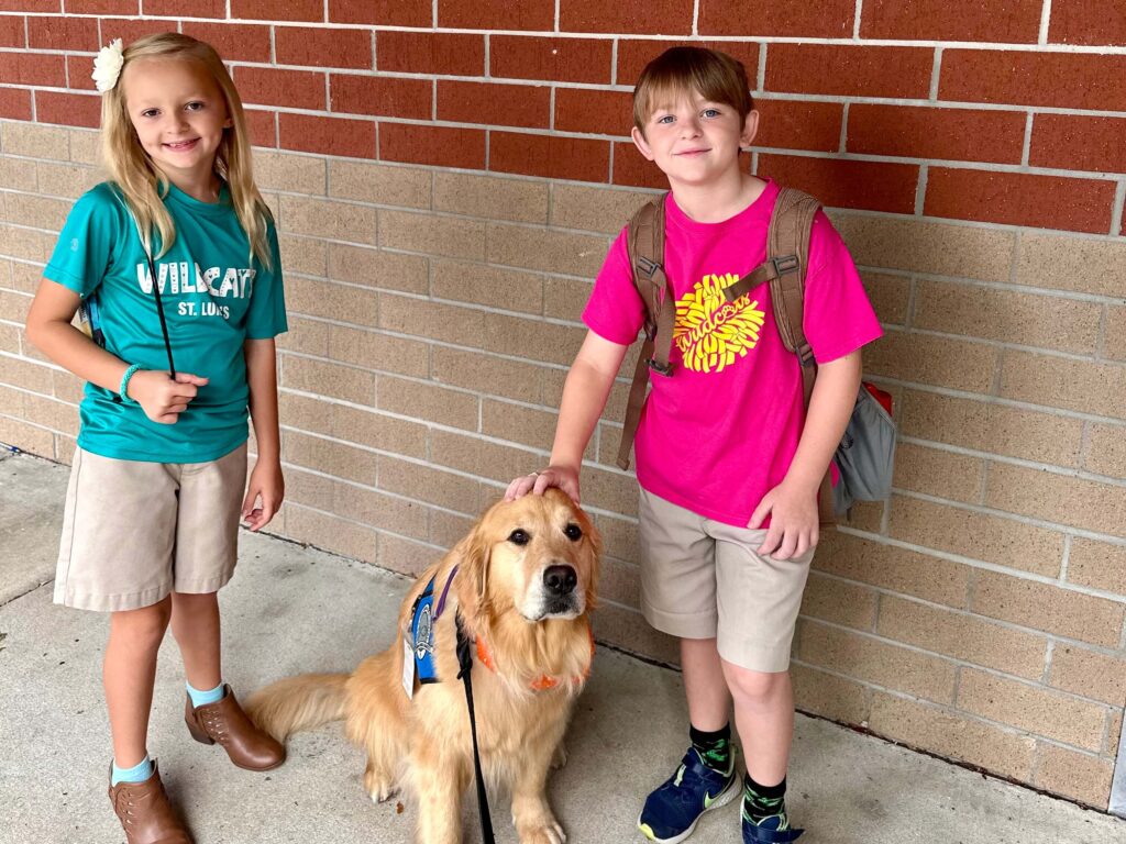 boy and girl petting a Golden Retriever dog