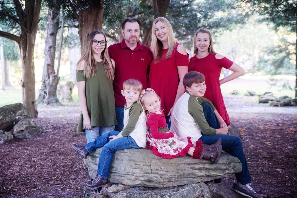 family of 7 sitting around a log in the woods