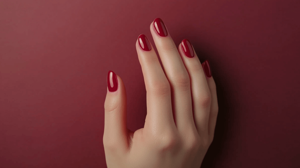 A deep burgundy manicure on a female hand, nails are short and polished to perfection.
