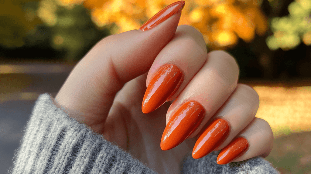 A burnt orange manicure on a female hand, nails are naturally shaped and sleek.
