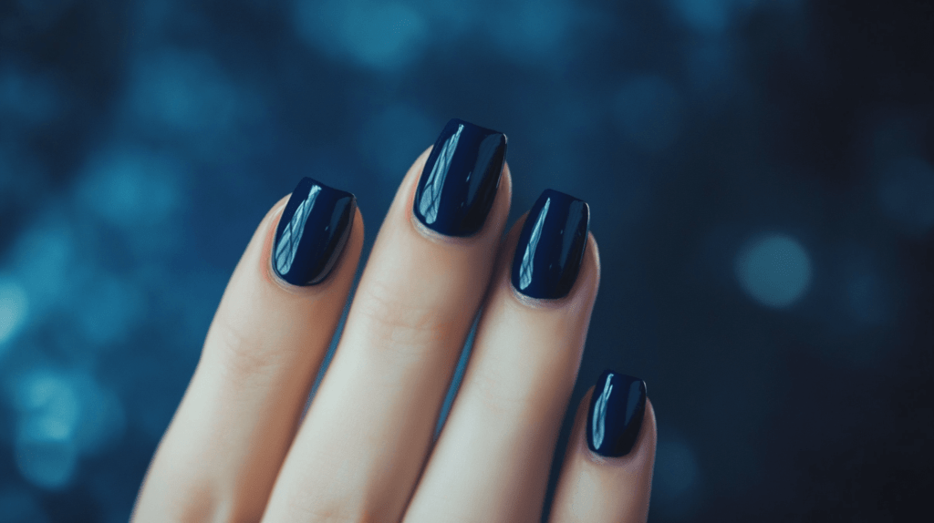 A navy blue manicure on a female hand, nails are slightly longer and perfectly shaped.
