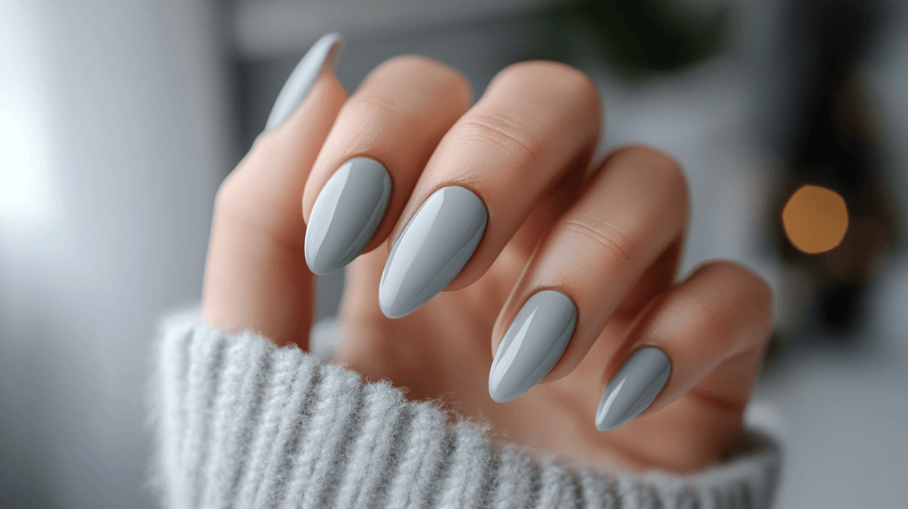 A soft grey manicure on a female hand, nails are short and naturally shaped.
