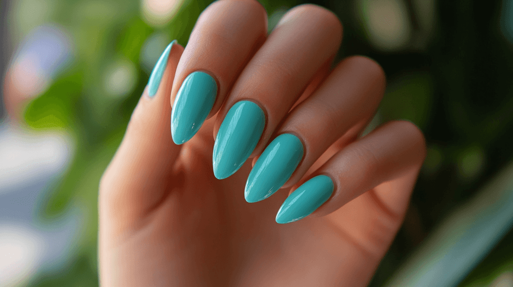 A turquoise manicure on a female hand, nails are medium-length and neatly shaped.
