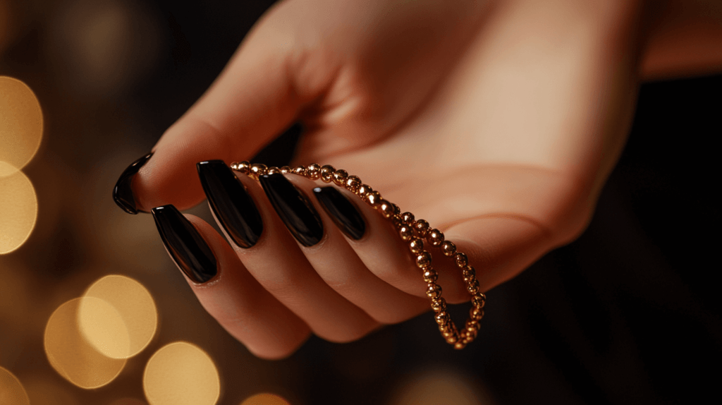 black nails holding a gold bead necklace