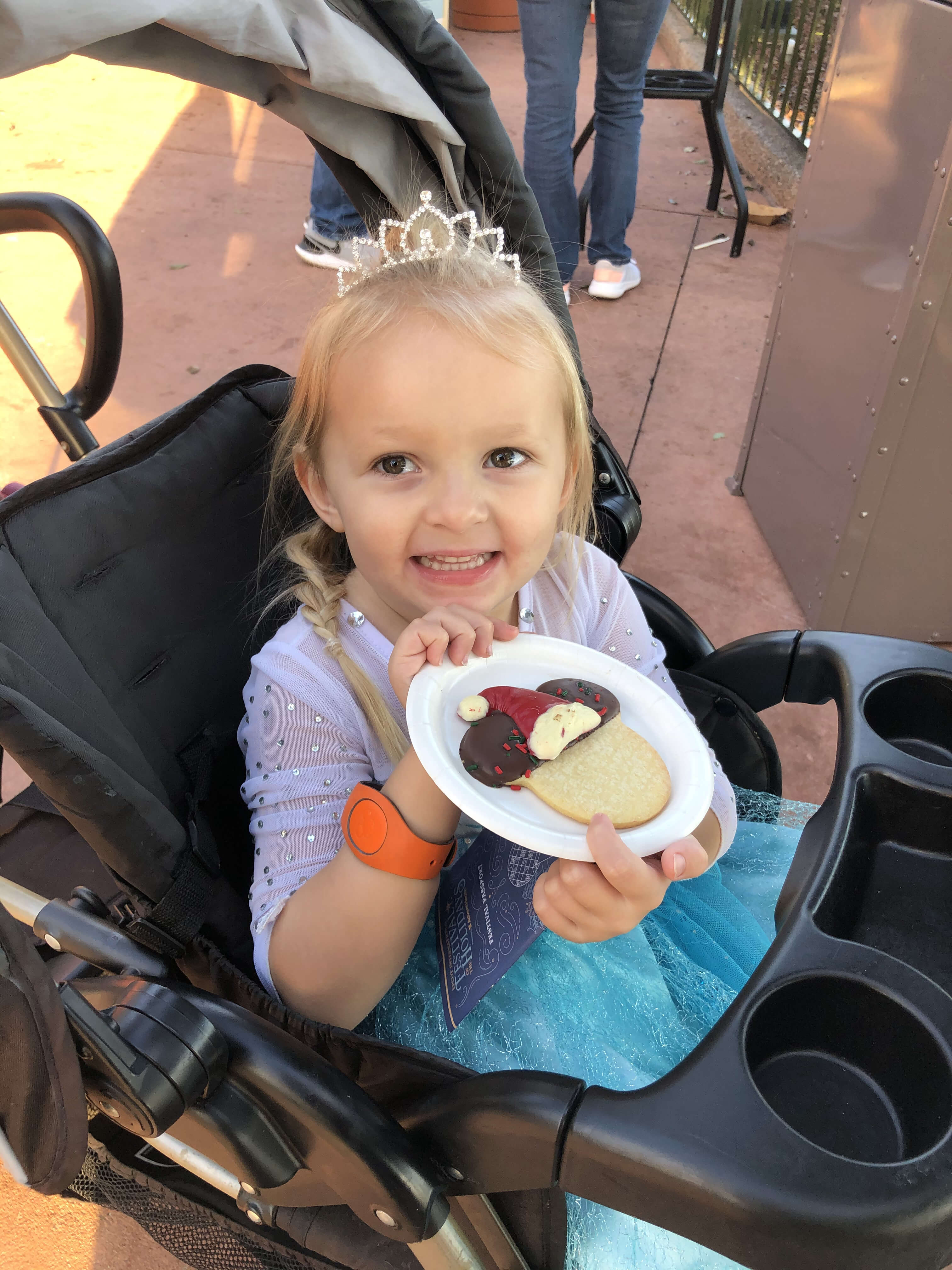 little girl in stroller with a mickey Mouse dessert