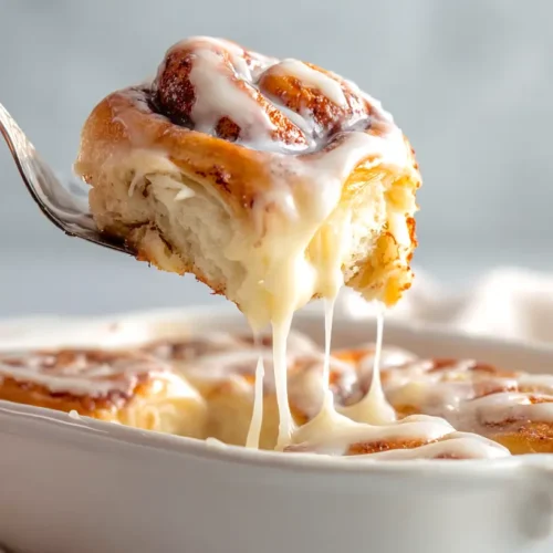 sourdough cinnamon roll being lifted from white pan