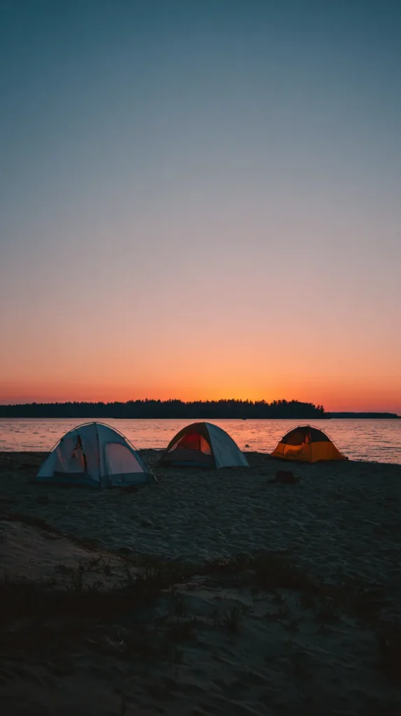 three tents camping on the beach at sunset