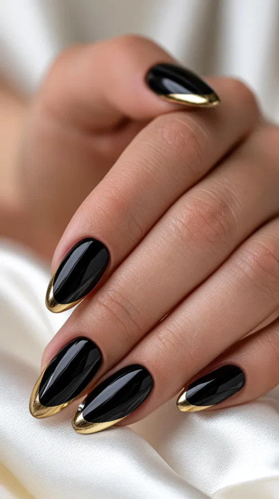 Detailed beauty shot of classy black and gold birthday nails, medium almond shape, glossy black polish, thin gold chrome French tips, tiny crystal accents, hand resting on a white satin surface beside gold birthday candles, moody but elegant celebration vibe, luxury nail photography, no face, no text, no watermark